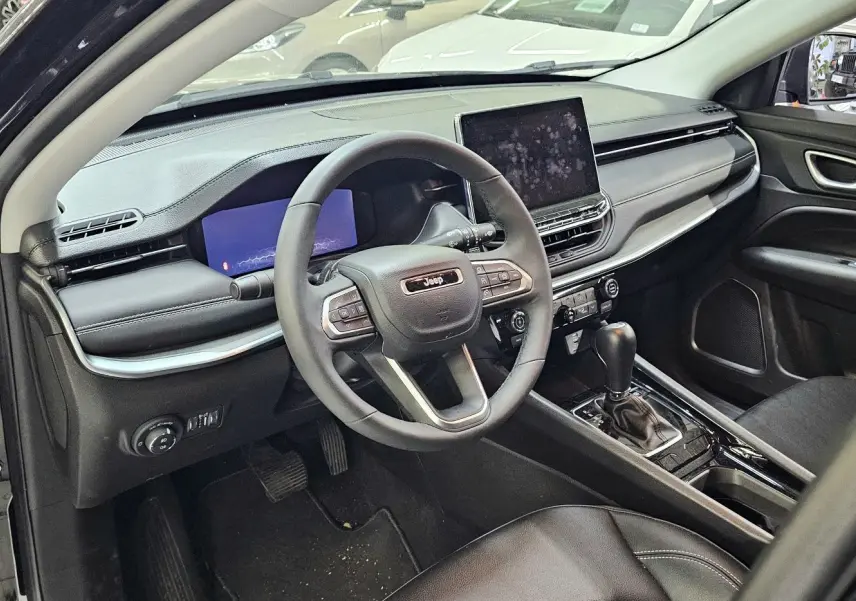 Intérieur noir du Jeep Compass 2023 vu côté conducteur, avec tableau de bord moderne et écran tactile central.
