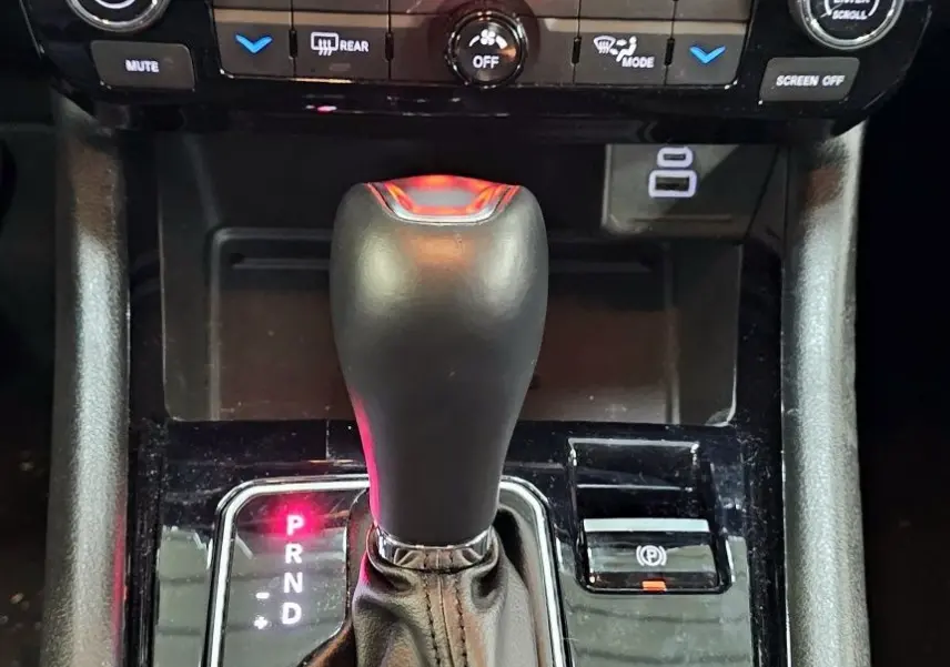 Gros plan sur la console centrale noire du Jeep Compass 2023, mettant en valeur le levier de vitesse automatique et les commandes climatiques.