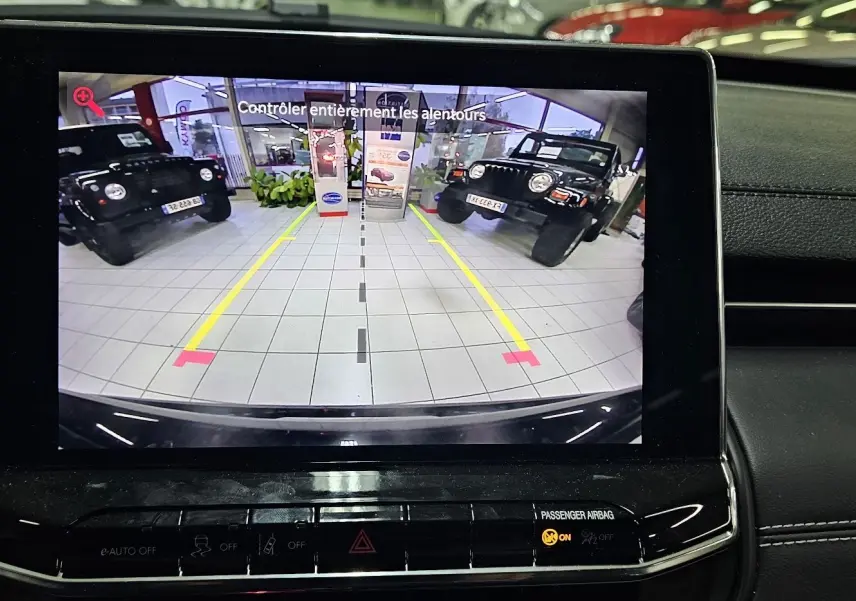 Vue arrière via caméra de recul du Jeep Compass noir dans un showroom avec deux autres Jeep noires visibles de chaque côté.