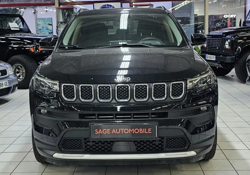Vue frontale d'un Jeep Compass noir 2023 dans un showroom, mettant en valeur sa calandre distinctive à sept fentes.