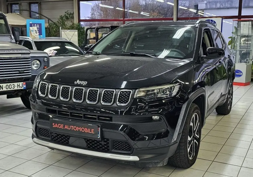 Jeep Compass noir en 3/4 avant droit dans un showroom, avec calandre distinctive à sept fentes et jantes alliage.
