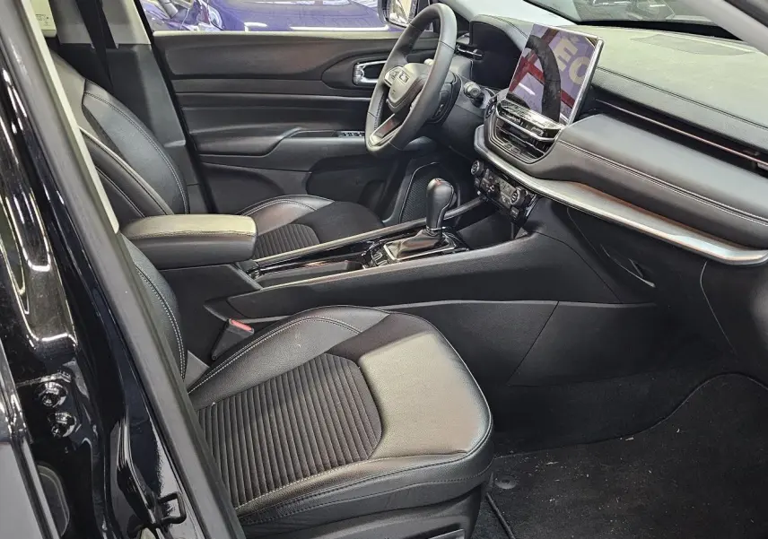 Intérieur noir du Jeep Compass 2023 vu côté conducteur, avec sièges cuir et tableau de bord moderne équipé d'un écran tactile.
