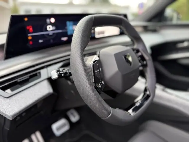 Gros plan sur le volant cuir multifonction GT et le tableau de bord numérique du Peugeot 3008 Hybrid Gris Titane, intérieur moderne.