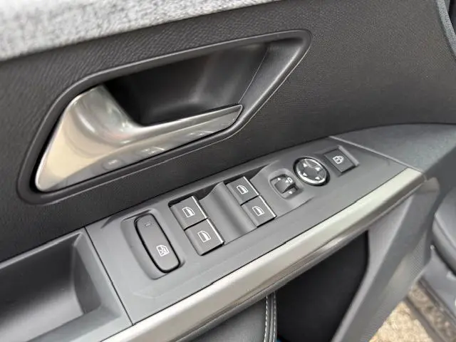 Gros plan sur la commande des vitres et rétroviseur côté conducteur du PEUGEOT 3008 HYBRID 145 gris titane.