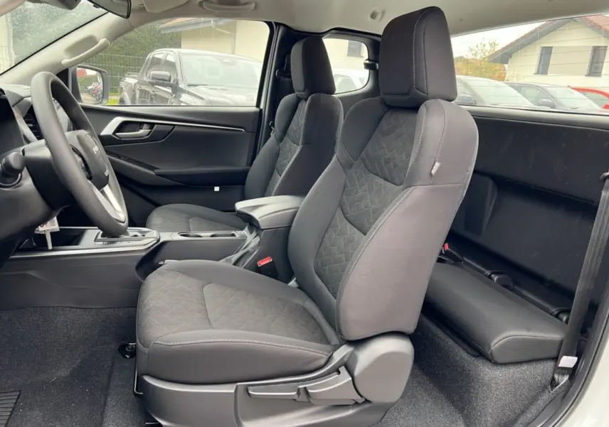 Vue intérieure côté gauche du pickup Isuzu D-MAX 2026 Splash White, montrant les sièges avant en tissu noir et l'accoudoir central.