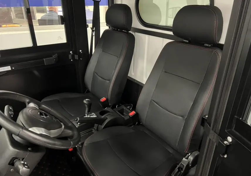 Intérieur de la LIBERTY L7e H2 CARGO 2025 vu côté conducteur, sièges noirs avec surpiqûres rouges et vitre arrière blanche.