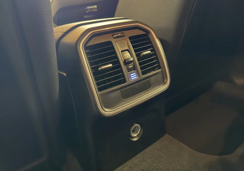 Détail de la console arrière noire du Porsche Macan S avec bouches d’aération et réglage de température éclairé.