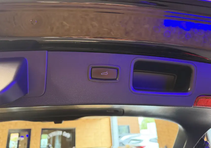 Bouton d'ouverture électrique du hayon sur la partie intérieure du coffre d'un Porsche Macan noir.