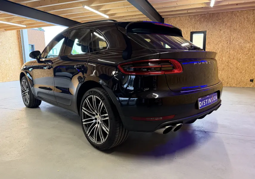 Vue 3/4 arrière droite d'un Porsche Macan S noir avec jantes alu 21 pouces et double sortie d'échappement sport.