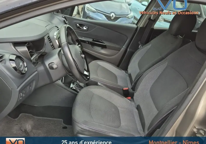 Intérieur avant du Renault Captur gris 2014, sièges tissu gris, volant cuir, tableau de bord et console visibles.