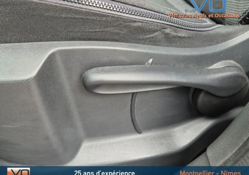 Poignée de réglage manuelle de siège en plastique noir à l'intérieur d'un Renault Captur gris, version 2014.