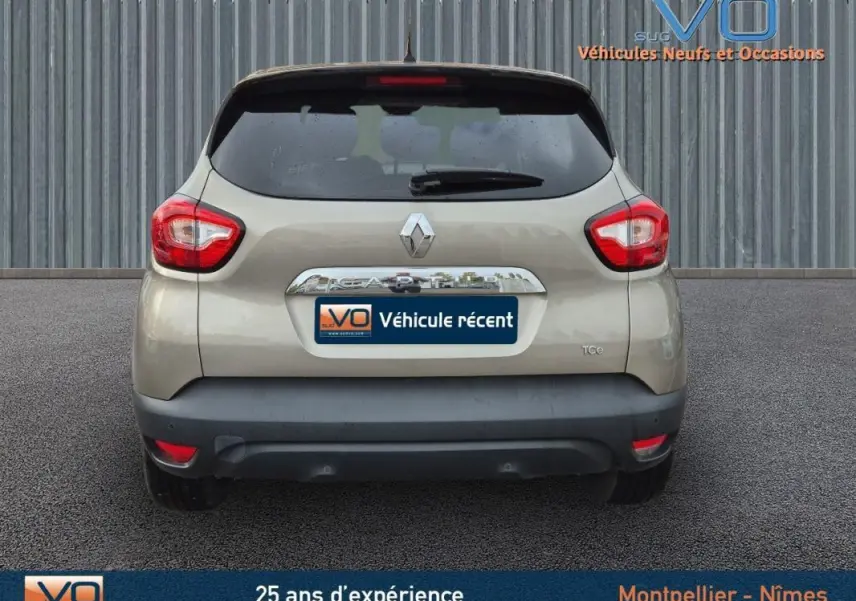 Vue arrière d'un Renault Captur gris clair avec vitres surteintées et feux arrière rouges visibles.