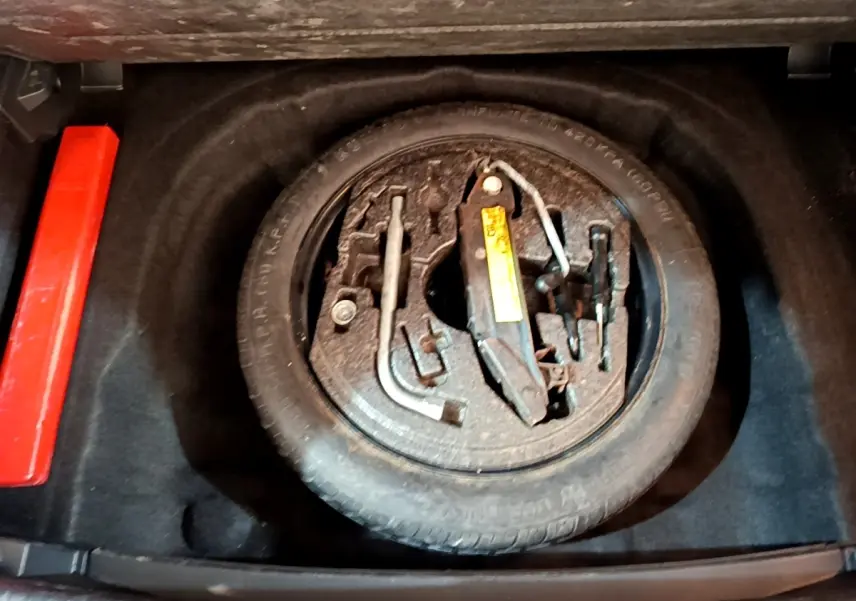 Vue plongeante sur la roue de secours et les outils de bord dans le coffre d'une Volkswagen Golf gris clair 2017