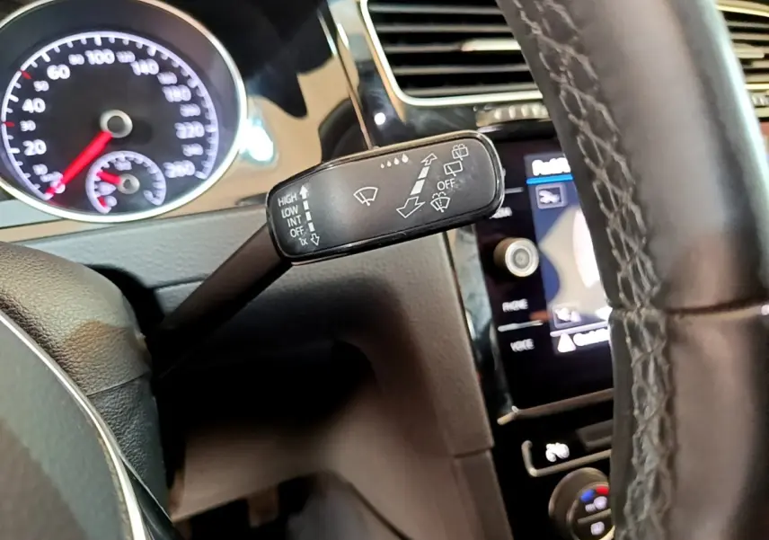 Gros plan sur la manette d’essuie-glace à gauche du volant cuir d’une Volkswagen Golf gris clair 2017.