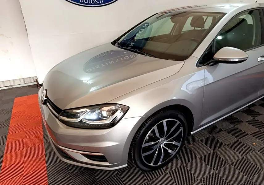 Vue 3/4 avant droit d'une Volkswagen Golf gris clair avec phares LED et jantes alliage distinctives.