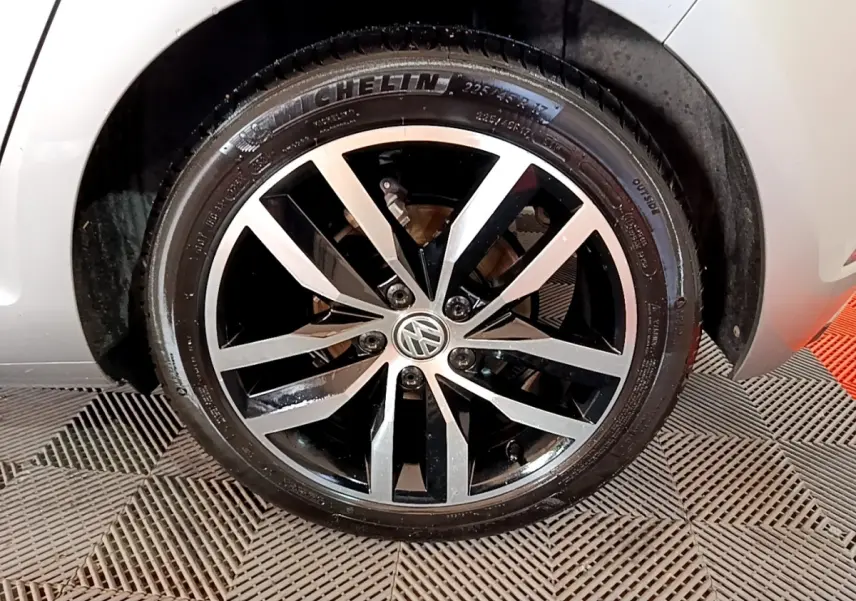 Gros plan sur la jante alliage bicolore noir et argent d'une Volkswagen Golf gris clair, roue avant droite visible.