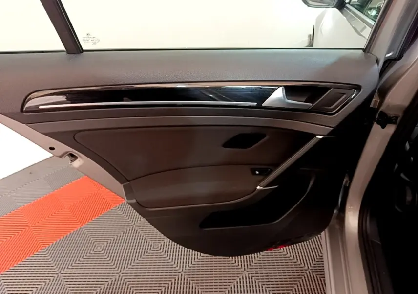 Vue de la porte arrière droite ouverte d'une Volkswagen Golf gris clair, avec garniture noire et insert décoratif brillant.