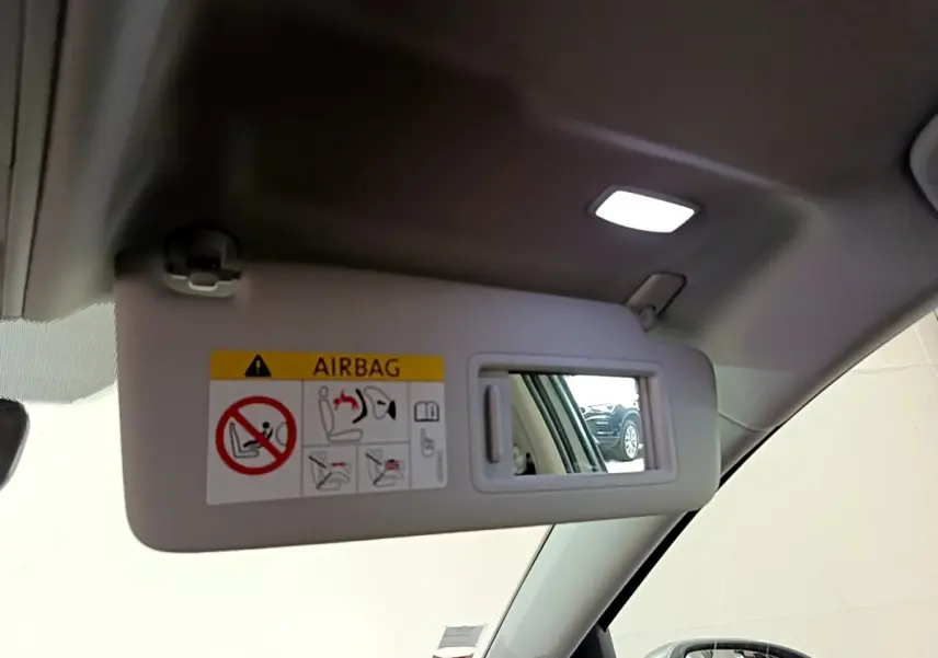 Miroir de pare-soleil côté conducteur dans un Volkswagen Golf gris clair, intérieur clair visible en reflet.