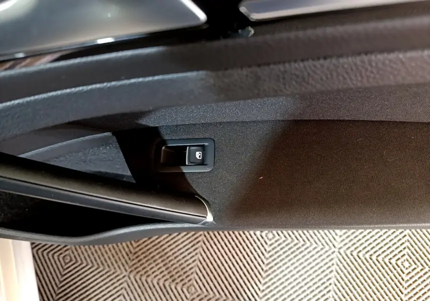 Bouton de verrouillage de porte sur la garniture intérieure côté conducteur d'une Volkswagen Golf gris clair, vue rapprochée.