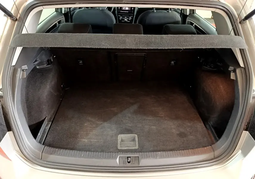 Vue arrière du coffre ouvert d'une Volkswagen Golf gris clair, montrant l'espace de chargement et la banquette arrière.