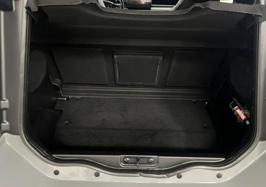 Coffre ouvert vu de dessus d'une LIGIER JS50 bleu 2026, montrant l'espace de rangement intérieur noir.