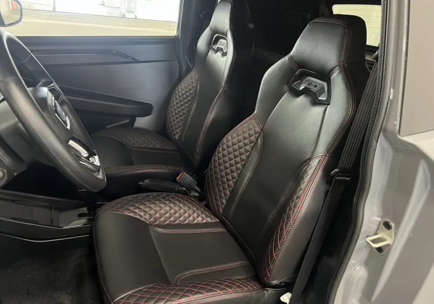 Vue intérieure côté conducteur de la LIGIER JS50 0.5 REVO D+ ULTIMATE avec sièges noirs à surpiqûres rouges.