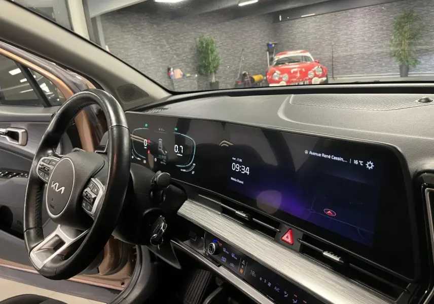Intérieur du Kia Sportage marron 2022, vue côté conducteur sur le tableau de bord numérique et volant cuir.