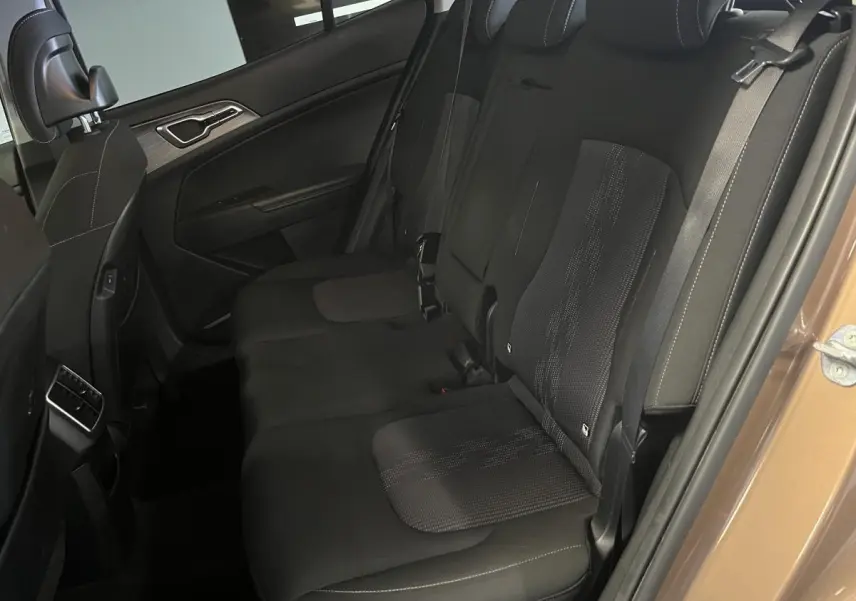 Vue côté droit de la banquette arrière noire du Kia Sportage marron 2022 avec appuie-têtes et ceintures visibles.