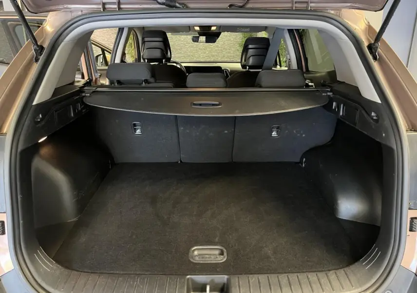Coffre ouvert d'un KIA Sportage marron 2022, vue arrière montrant la plage arrière et les sièges noirs.