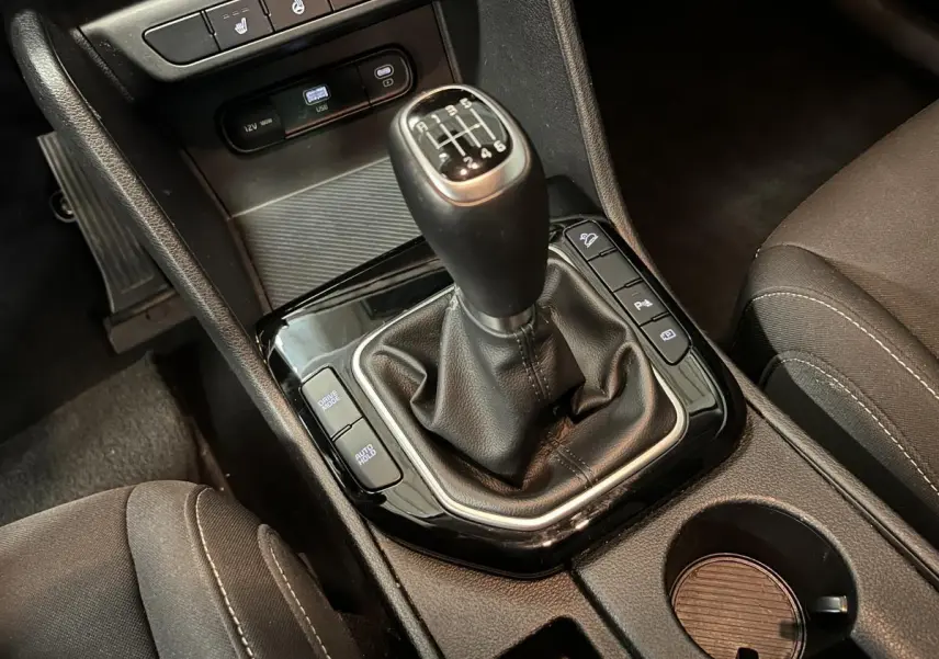 Gros plan sur la console centrale noire du Kia Sportage 2022 avec levier de vitesse manuel et boutons fonctionnels.