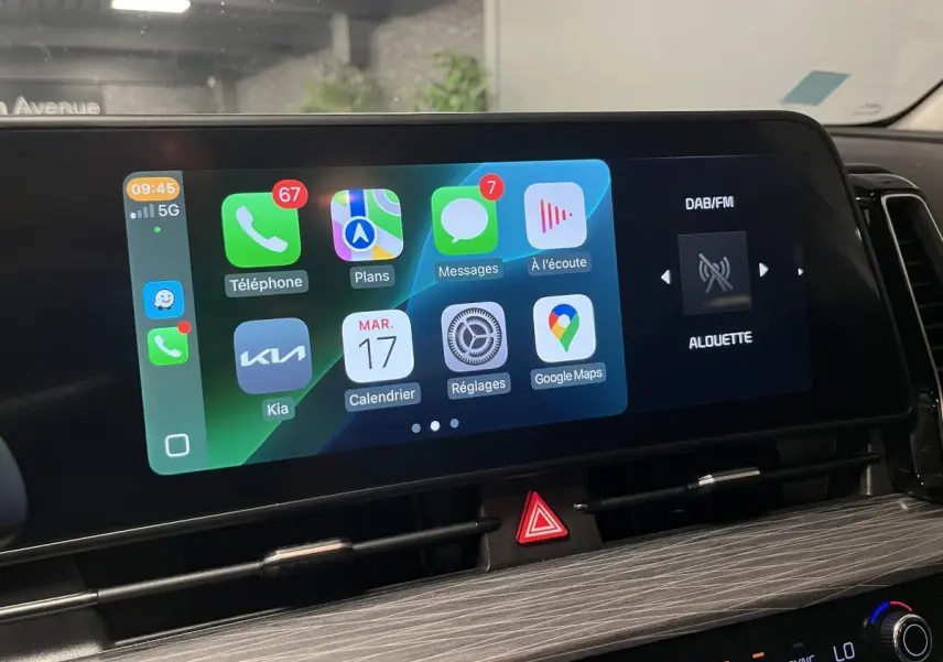Écran tactile central du Kia Sportage 2022 montrant interface Apple CarPlay et radio DAB/FM en intérieur noir.