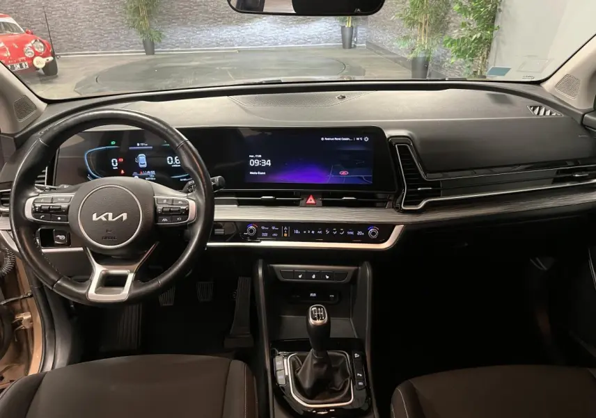Intérieur du Kia Sportage 2022, vue de face sur tableau de bord noir avec écran tactile et levier de vitesses manuel.