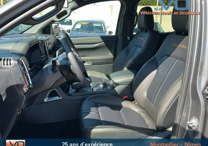 Vue intérieure côté conducteur du Ford Ranger Wildtrak gris 2025, avec sièges cuir noirs brodés et console centrale équipée.