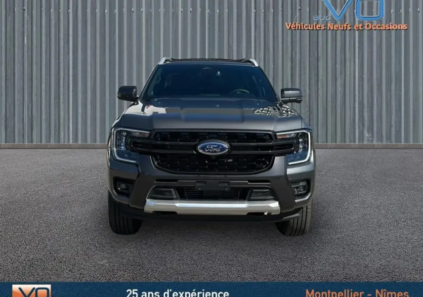 Vue frontale d'un Ford Ranger gris 2025 avec calandre noire, barres de toit et vitres surteintées visibles.