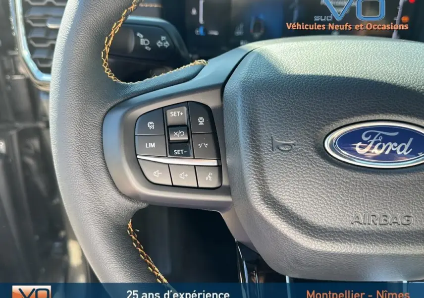 Gros plan sur le volant multifonctions noir avec surpiqûres jaunes du Ford Ranger gris 2025, mettant en valeur les commandes intégrées.