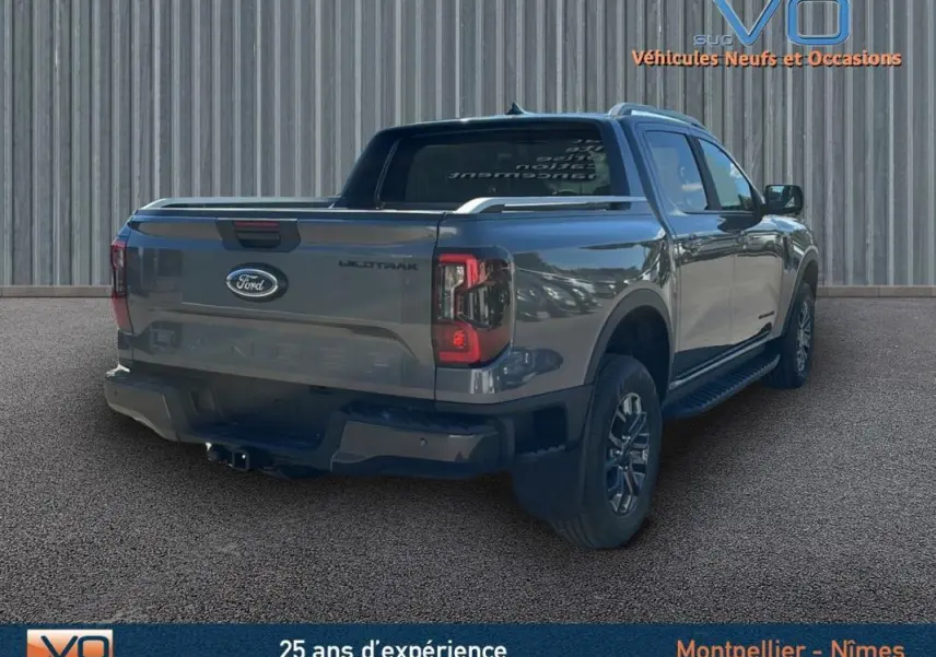 Ford Ranger Wildtrak gris vu en 3/4 arrière droit avec barres de toit et vitres surteintées.