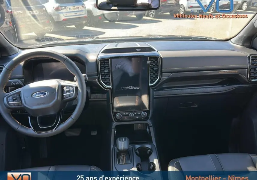 Vue intérieure avant du Ford Ranger Wildtrak 2025 avec volant multifonctions, écran tactile vertical et sellerie noire.