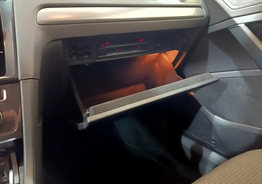 Gros plan sur la boîte à gants ouverte avec éclairage intérieur dans l'habitacle noir de la Volkswagen Golf 2018.