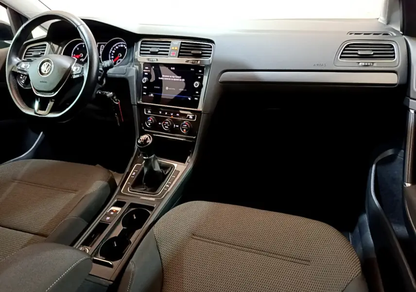 Intérieur de Volkswagen Golf 1.6 TDI 2018 vu côté passager, tableau de bord noir avec écran tactile et boîte manuelle.