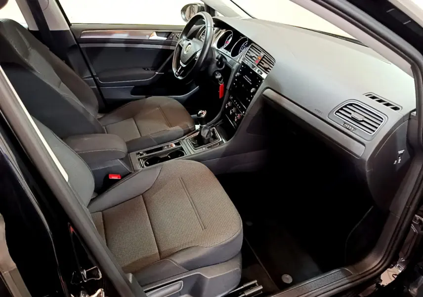 Intérieur de la Volkswagen Golf noir 2018, vue côté conducteur, sièges tissu gris et tableau de bord moderne.