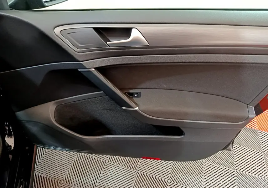 Vue rapprochée de la porte intérieure côté gauche noire de la Volkswagen Golf 1.6 TDI 2018 avec insert bois.