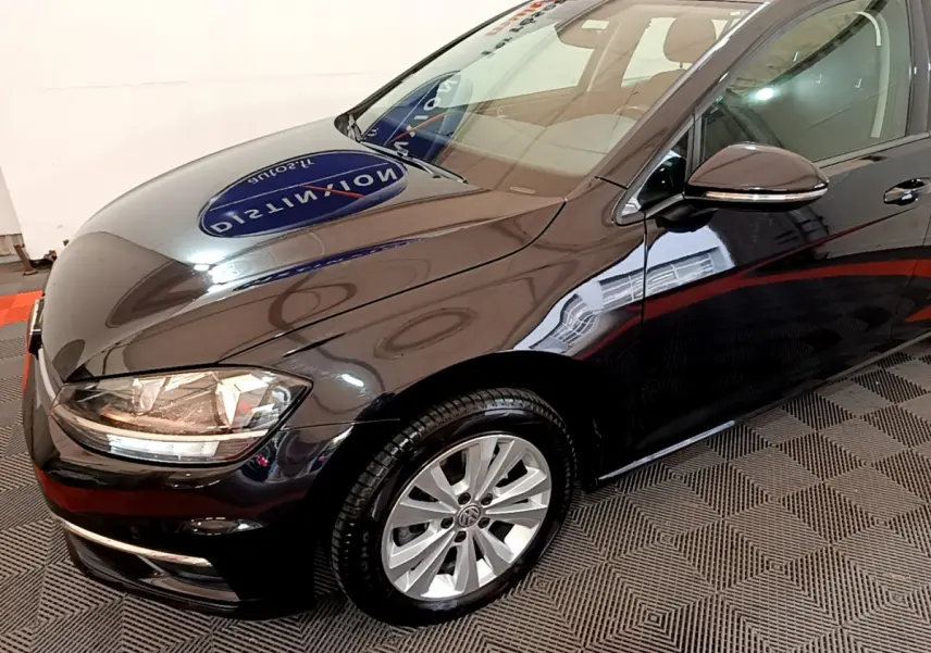 Vue 3/4 avant droit d'une Volkswagen Golf noire 2018 avec phares halogènes et jantes alliage argentées.