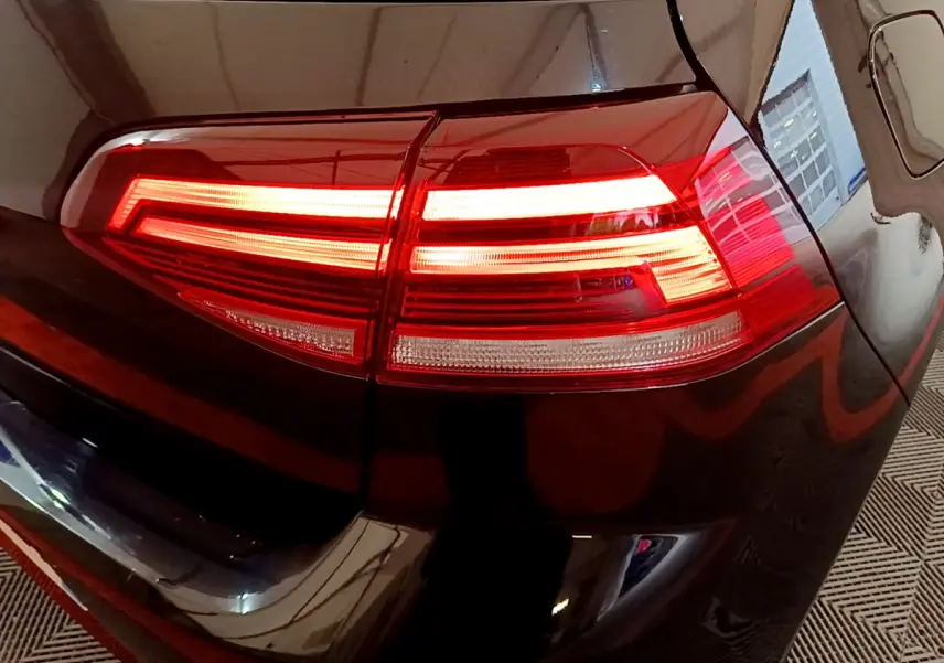 Gros plan sur le feu arrière droit allumé d'une Volkswagen Golf noire, soulignant ses lignes LED distinctives.