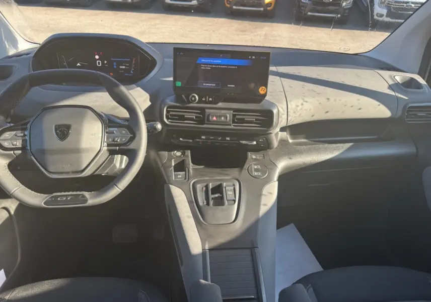 Vue intérieure avant du Peugeot Rifter GT Plus 2025, tableau de bord moderne avec écran tactile central et volant cuir multifonctions.