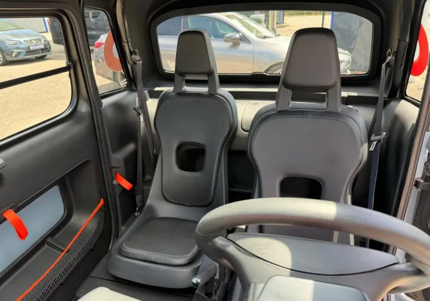 Vue intérieure avant de la Citroën Ami MY AMI POP 2024 avec sièges noirs minimalistes et volant visible.