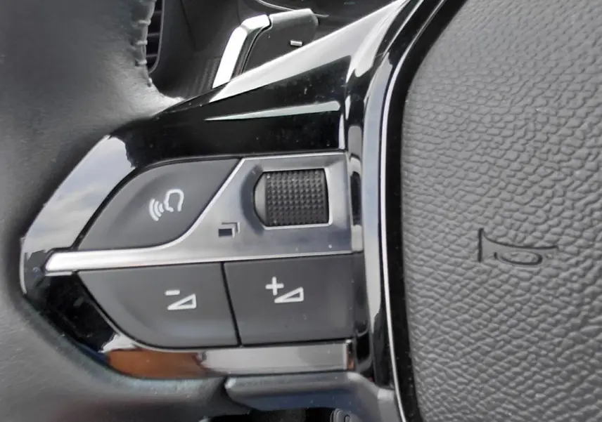 Gros plan sur les commandes de volume et appel vocal sur le volant noir du Peugeot 2008 Hybrid 145 e-DCS6 Style 2025.
