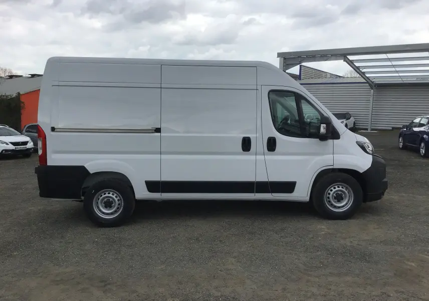 Profil latéral droit d'un utilitaire Peugeot Boxer blanc, modèle L2H2, avec portes coulissantes et pare-chocs noirs.