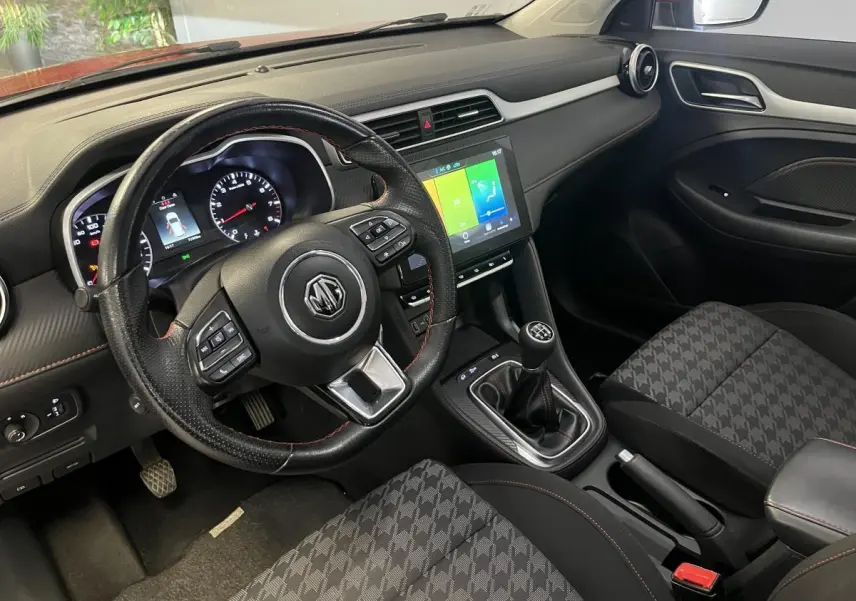 Intérieur de MG ZS 2022 vu côté conducteur, volant cuir avec surpiqûres rouges et écran tactile central.
