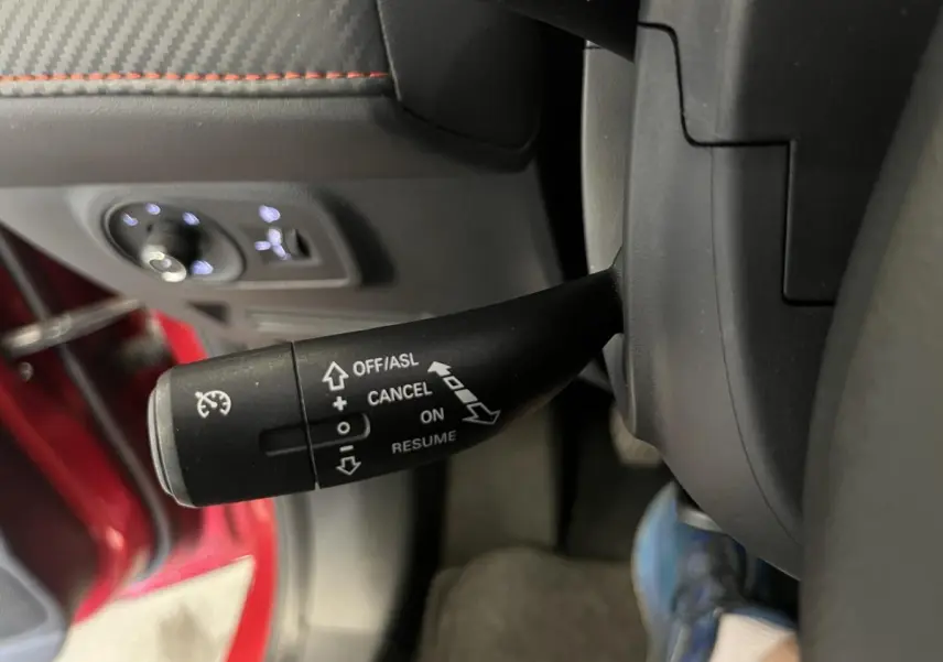 Le levier de régulateur de vitesse du MG ZS rouge 2022 visible côté gauche du volant, avec commandes éclairées.