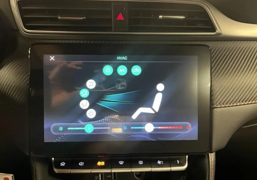 Écran tactile central affichant la climatisation dans l'habitacle du MG ZS rouge, avec tableau de bord en carbone.